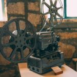 Stary metalowy projektor filmowy z szpulami stojący na białym stole