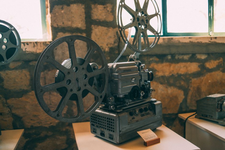Stary metalowy projektor filmowy z szpulami stojący na białym stole