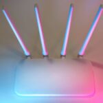 Biały router z czterema antenami oświetlony niebieskim i różowym światłem