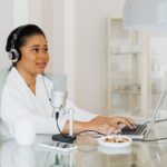 Kobieta w słuchawkach nagrywa podcast przy mikrofonie i laptopie