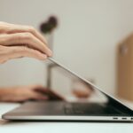Dłoń zamykająca pokrywę laptopa na biurku