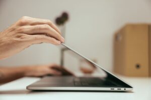 Dłoń zamykająca pokrywę laptopa na biurku