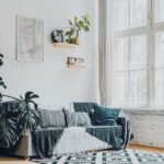 Jasny salon z dużą monsterą, kanapą przy oknie i półkami na ścianie