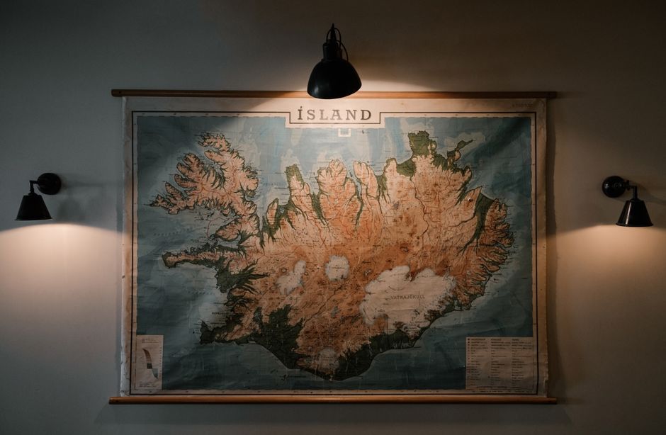 Stara mapa Islandii wisząca na ścianie oświetlona trzema lampami