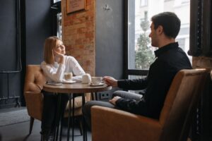 Kobieta i mężczyzna siedzą przy stoliku w kawiarni i rozmawiają