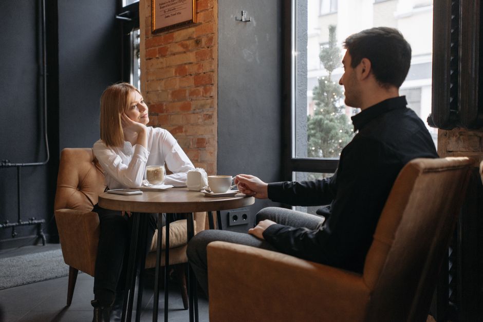 Kobieta i mężczyzna siedzą przy stoliku w kawiarni i rozmawiają