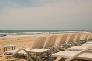 Puste białe leżaki ustawione w rzędzie na piaszczystej plaży przy morzu