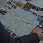 Osoba w zimowej kurtce trzyma rozłożoną mapę turystyczną Estonii