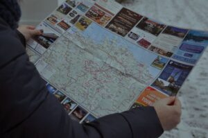 Osoba w zimowej kurtce trzyma rozłożoną mapę turystyczną Estonii