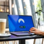 Otwarty laptop z aktywnym połączeniem VPN na ekranie w kawiarni.