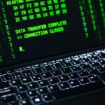 Podświetlana klawiatura laptopa z zielonym tekstem o transferze danych na ekranie