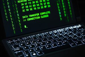 Podświetlana klawiatura laptopa z zielonym tekstem o transferze danych na ekranie