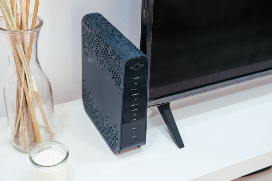 Czarny router NOS stojący na białej szafce obok telewizora