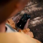 Smartfon z ikoną rozładowanej baterii trzymany w dłoniach