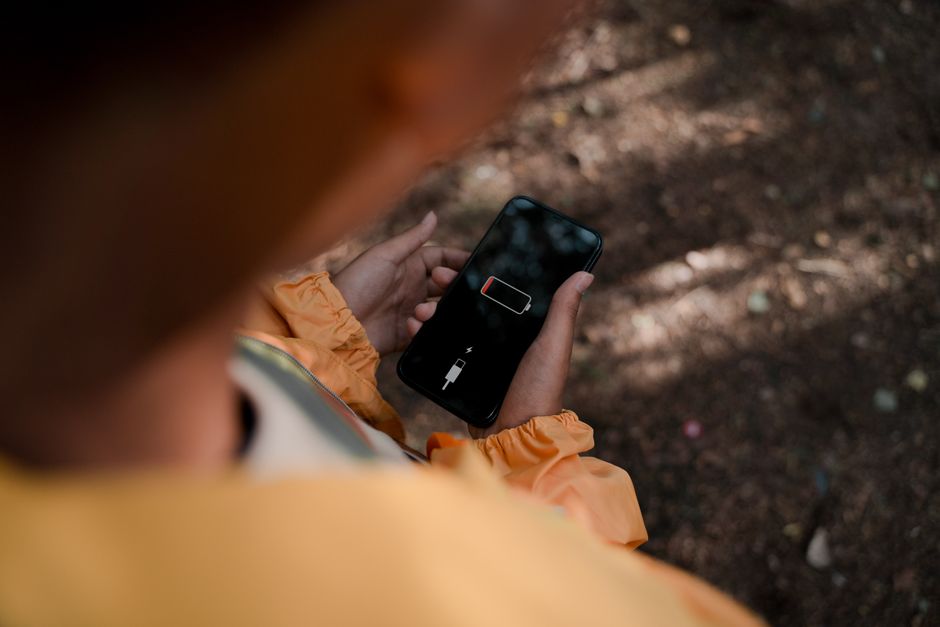 Smartfon z ikoną rozładowanej baterii trzymany w dłoniach