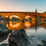 Kamienny most rzymski nad rzeką w świetle zachodzącego słońca